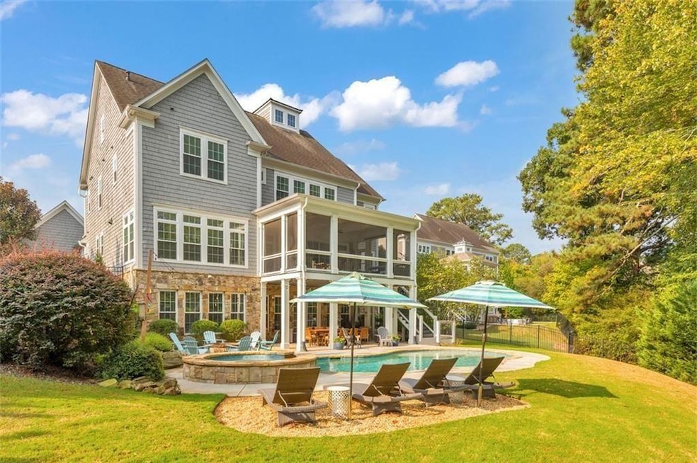 Back of house featuring a sunroom, a patio area, stone siding, and a pool with connected hot tub