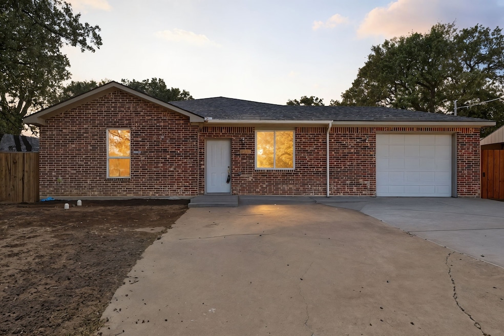 Single story home with an attached garage, concrete driveway, brick siding, and a shingled roof