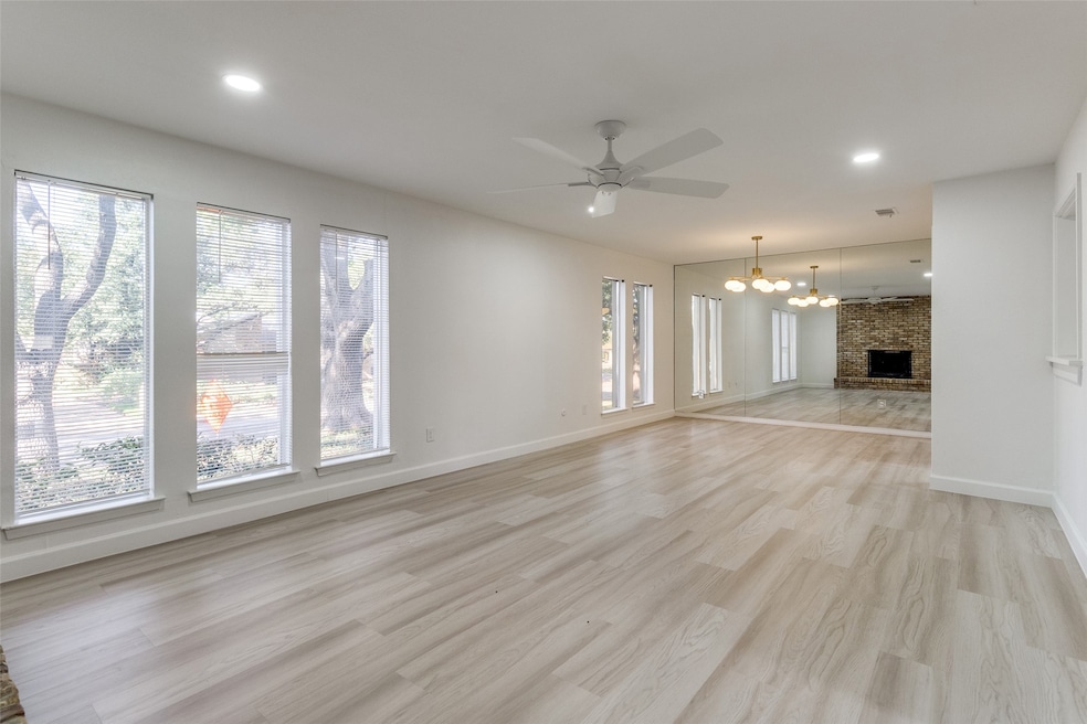 Unfurnished living room featuring light wood-style flooring, recessed lighting, a chandelier, a fireplace, and ceiling fan