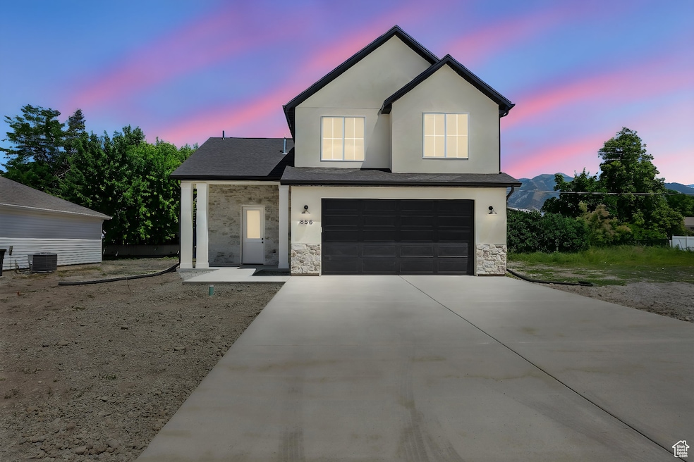 Traditional-style home featuring a garage, driveway, stone siding, stucco siding, and roof with shingles