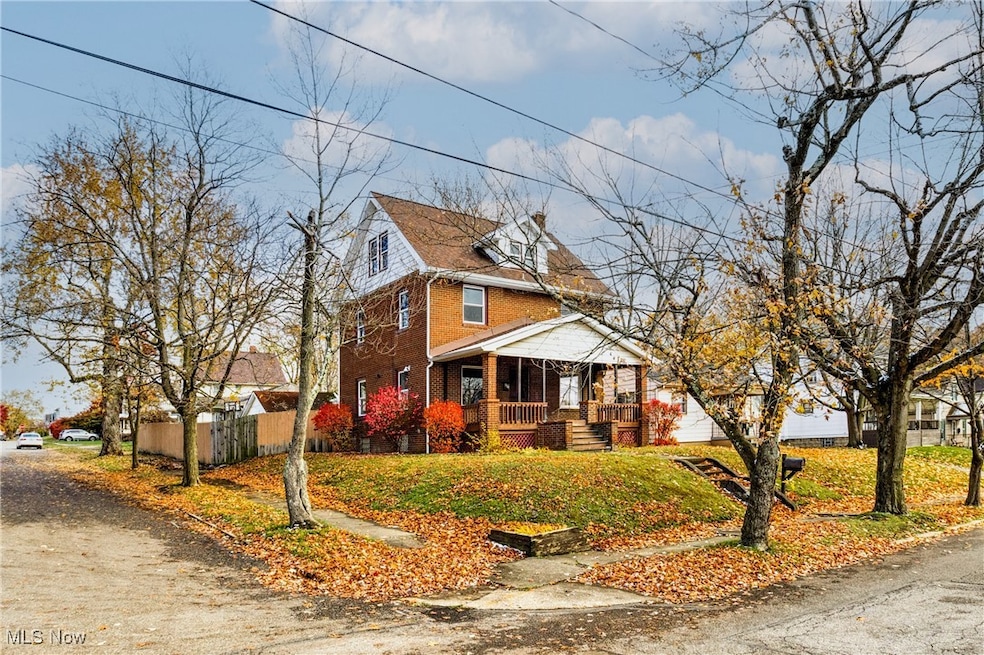 View of front facade featuring covered porch, brick siding, and a front lawn