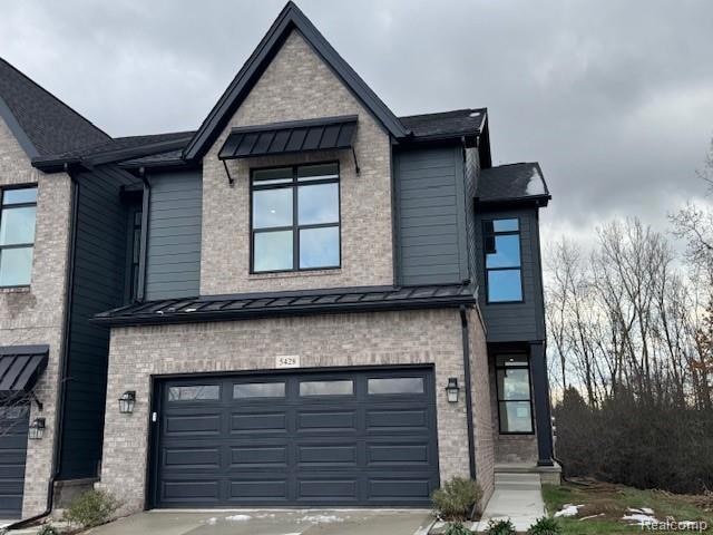 View of front of property with a standing seam roof, a metal roof, a garage, and brick siding