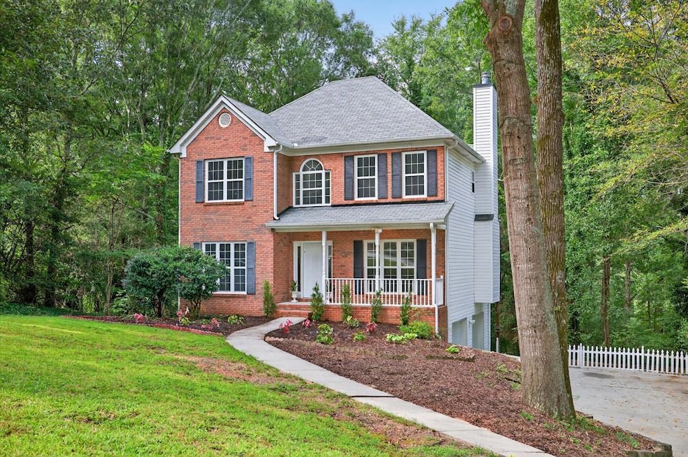 Colonial home featuring a chimney, a front yard, covered porch, and brick siding