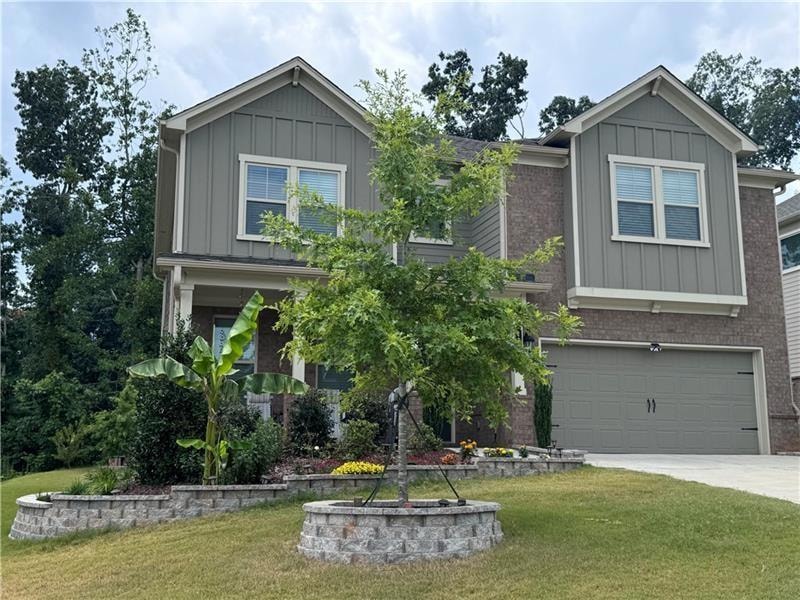 Craftsman house featuring board and batten siding, a garage, a front lawn, and concrete driveway