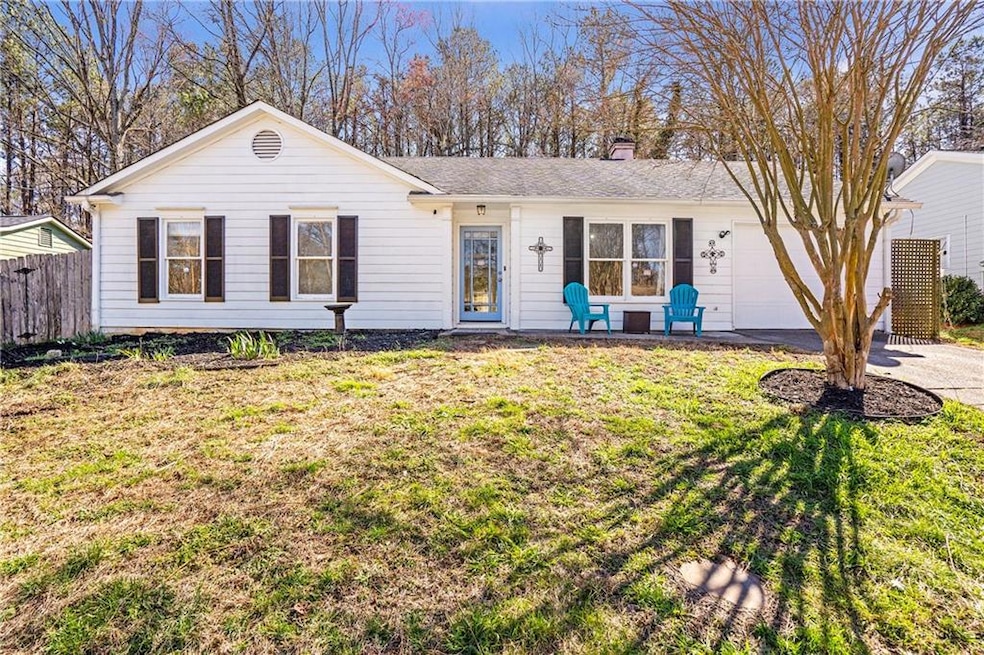 Ranch-style house with a garage, driveway, a chimney, and a shingled roof