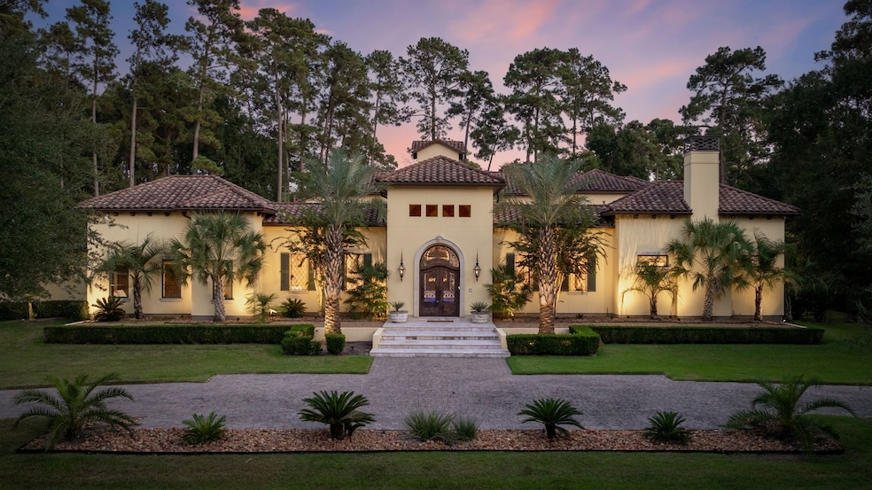 Framed by stately palms and warm evening light, this stunning Mediterranean-style home makes a striking first impression.