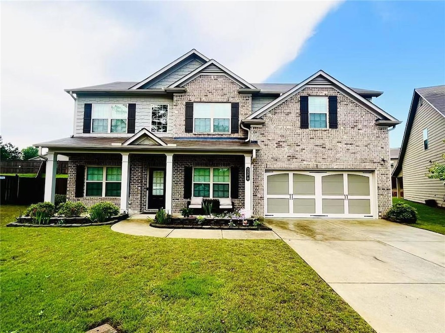 Craftsman house featuring a garage, brick siding, driveway, and a front yard