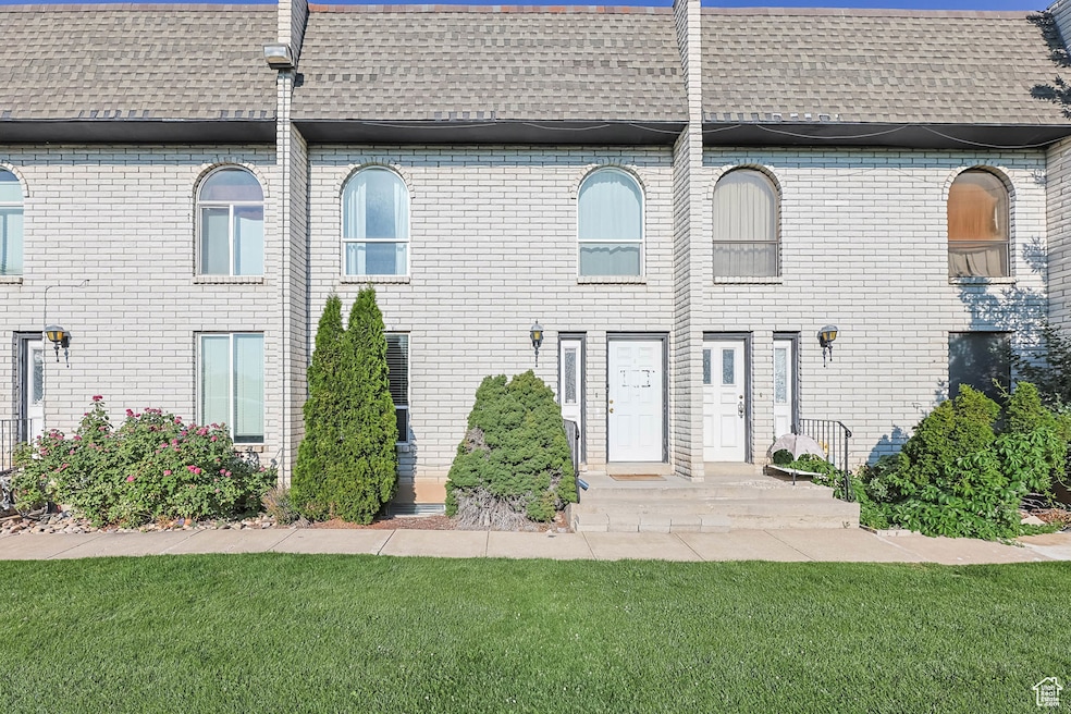 View of front of property with roof with shingles, a front lawn, and brick siding
