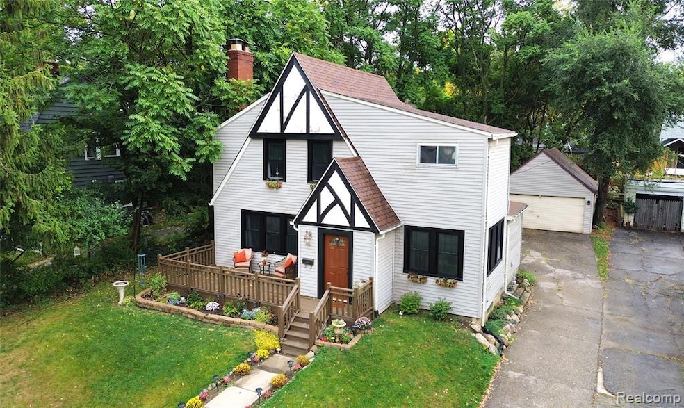 English style home with a front lawn, an outdoor structure, a detached garage, and a chimney