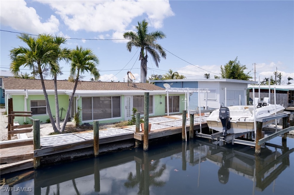 Rear view of house featuring boat lift and a pergo