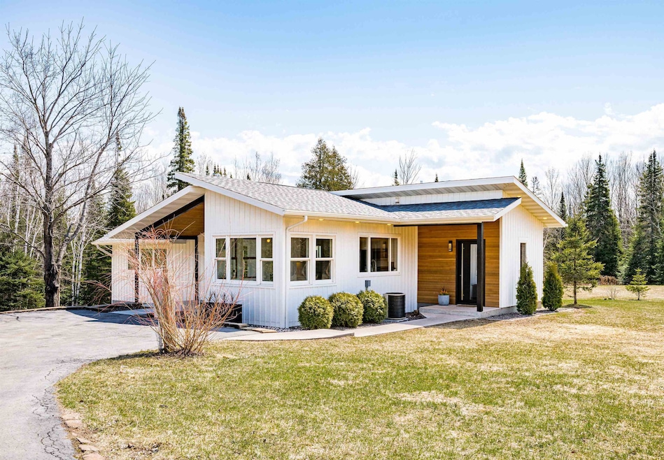 View of front of house with driveway, roof with sh