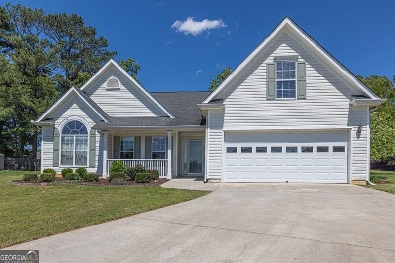 Traditional-style house with concrete driveway, a porch, a front lawn, and a garage