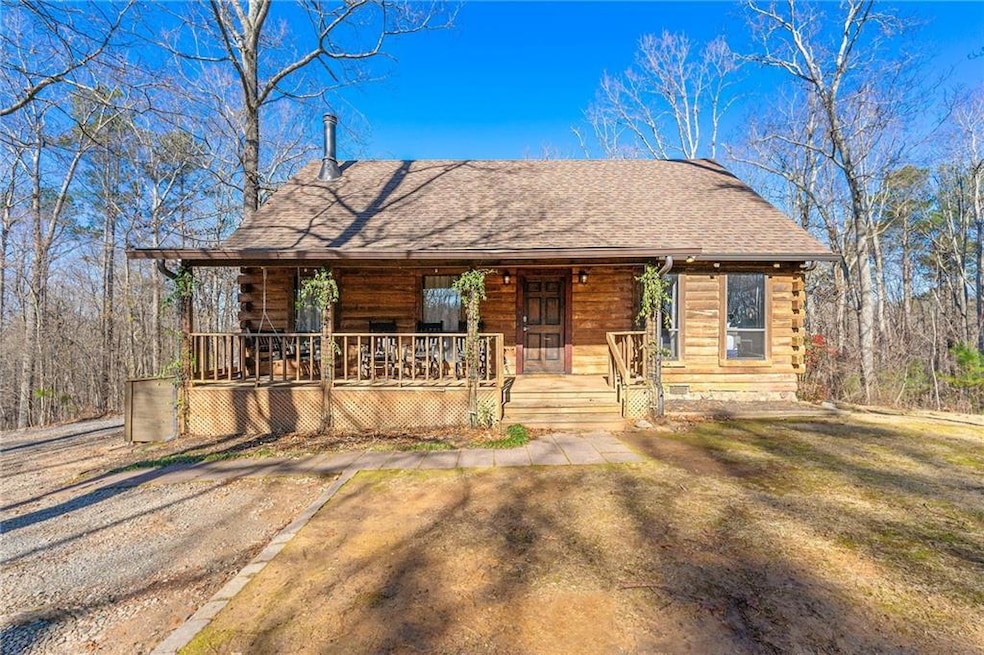 Log cabin featuring covered porch and a front yard
