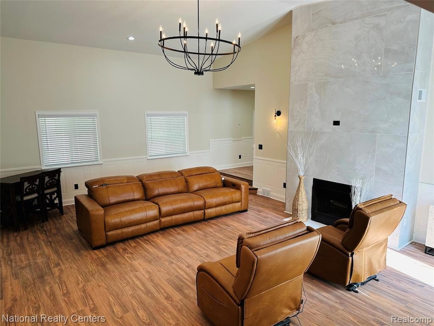 Living room featuring wood finished floors, a chandelier, a tile fireplace, and recessed lighting