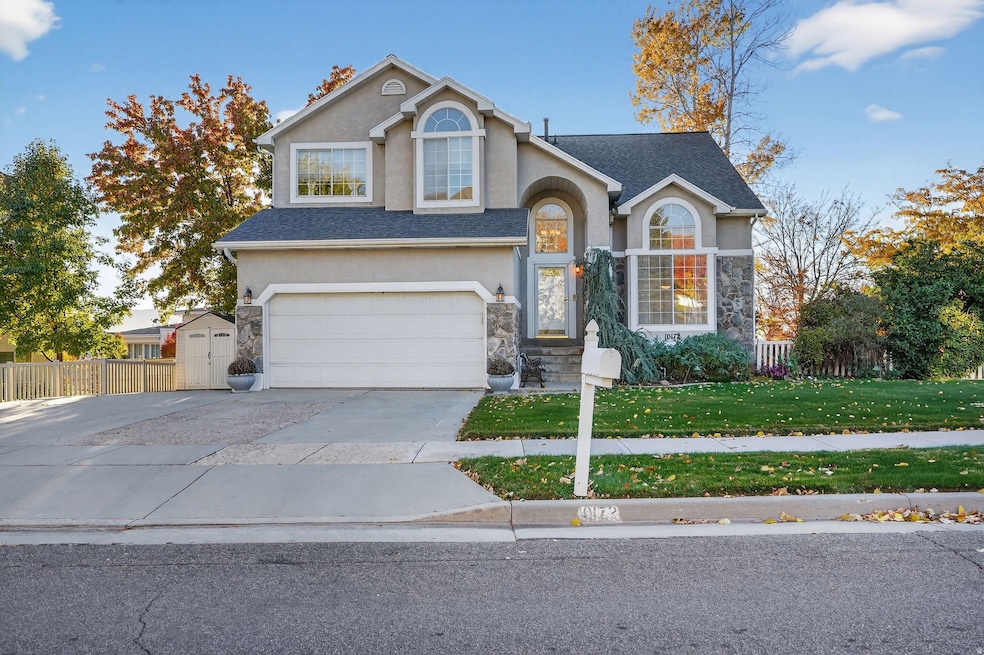 Traditional-style house with stucco siding, a garage, driveway, stone siding, and roof with shingles