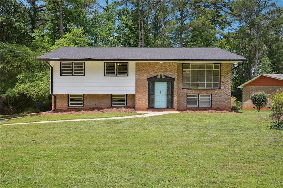 Raised ranch featuring a front yard and brick siding
