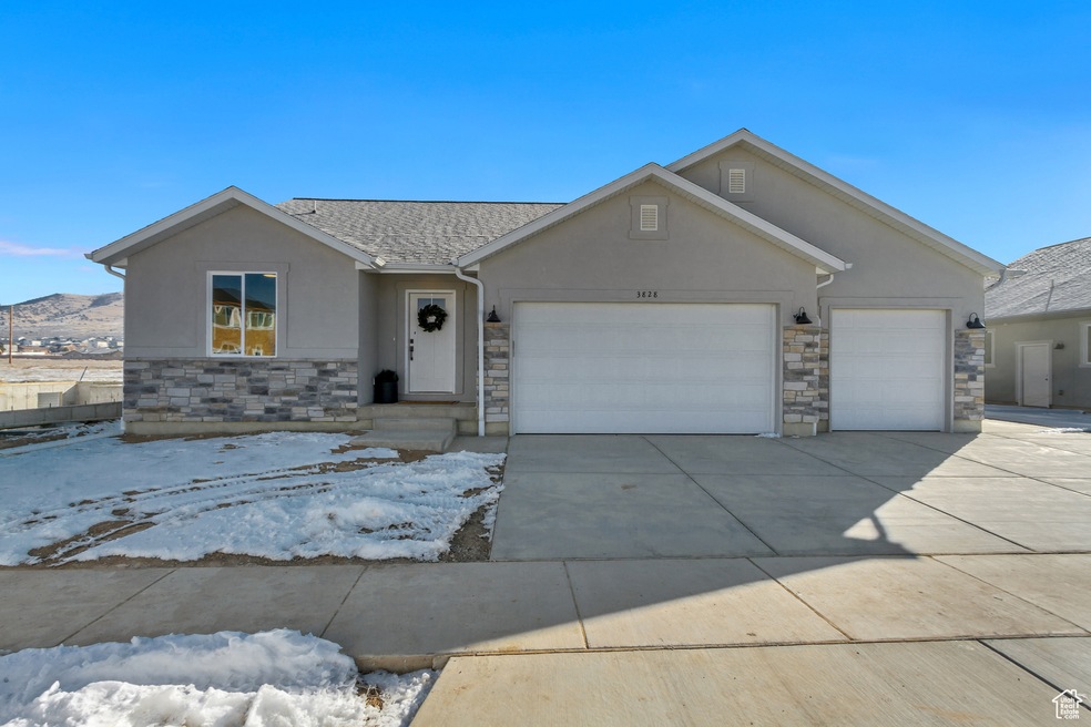 Single story home featuring stucco siding, stone siding, and driveway