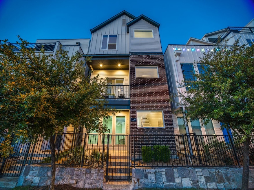 View of front facade with a balcony, brick siding, a fenced front yard, and board and batten siding