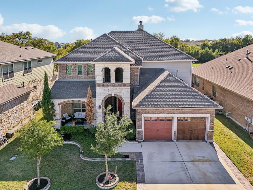 French country home featuring brick siding, driveway, an attached garage, and a front yard