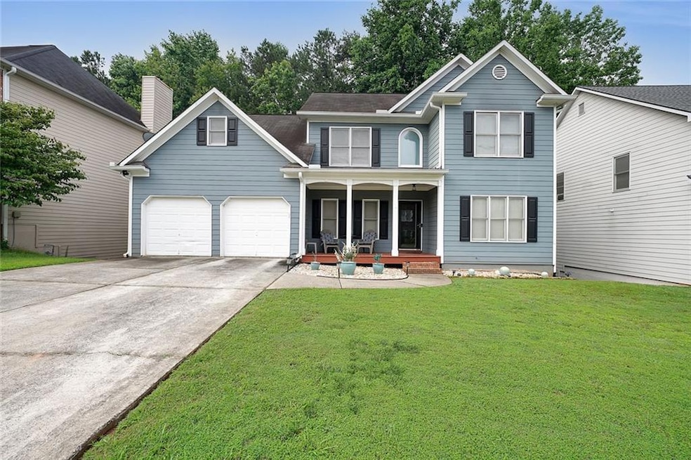 Traditional home featuring a porch, a front lawn, driveway, and an attached garage