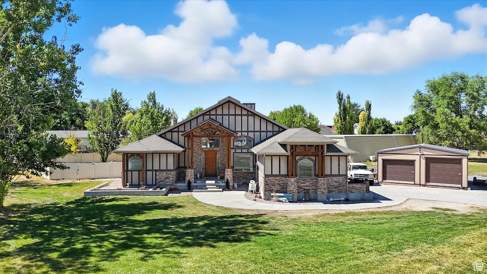 Tudor house featuring board and batten siding, stone siding, a front yard, and a garage