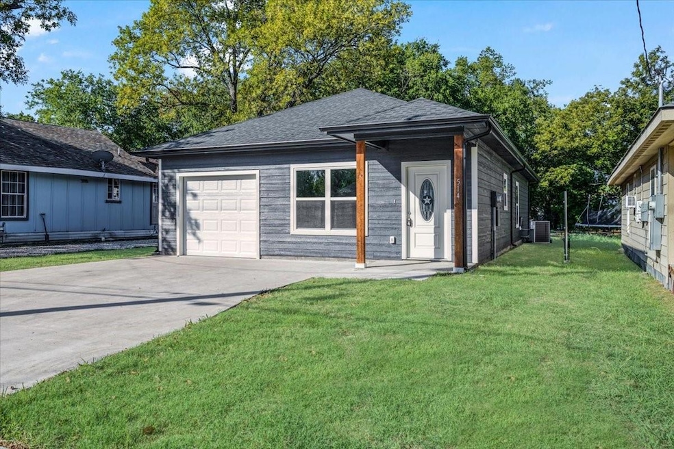 View of front facade featuring a front yard, central air condition unit, and a garage
