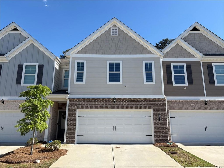 Townhome / multi-family property featuring brick siding, driveway, and a garage