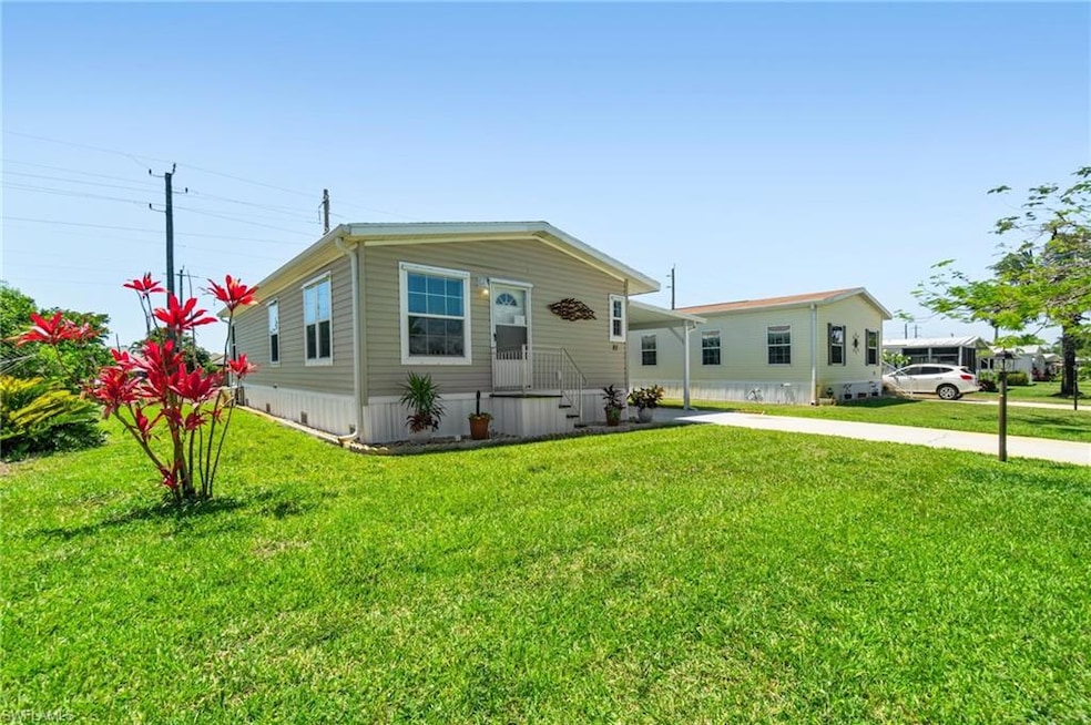 Manufactured / mobile home featuring an attached carport and a front lawn