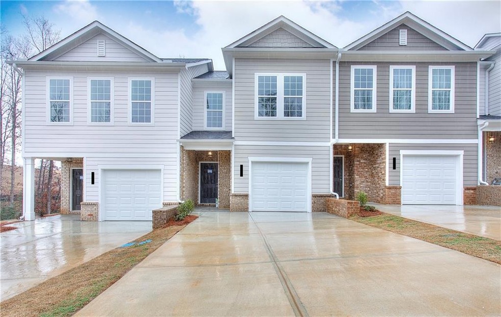 View of front facade featuring brick siding, driveway, and a garage