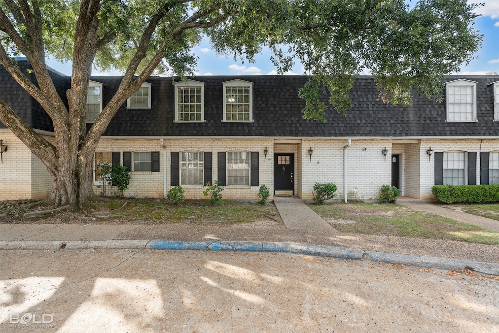 View of property featuring roof with shingles, mansard roof, and brick siding