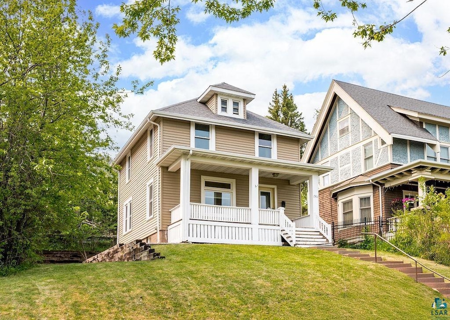 Traditional style home featuring covered porch and a front lawn