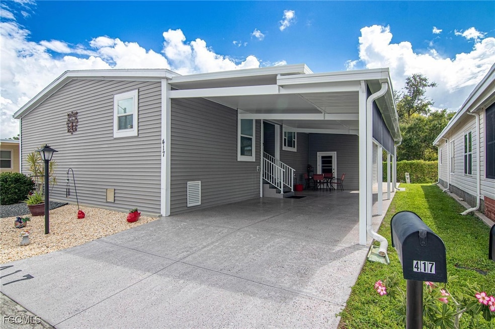 View of front facade featuring a carport, concrete driveway, and a patio area