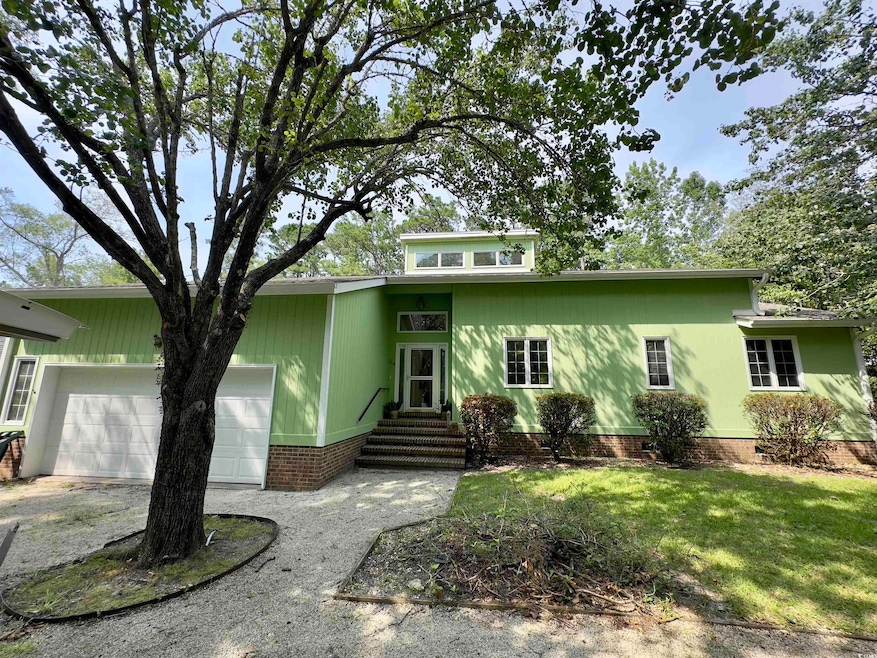 Mid-century home featuring an attached garage, entry steps, a front lawn, and driveway