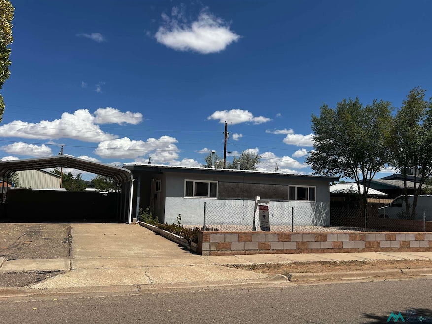 View of front of house featuring a carport, a fenced front yard, and concrete driveway