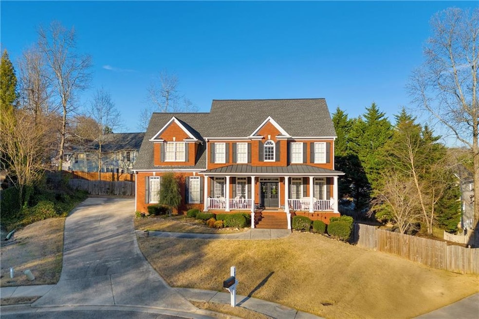 View of front of home featuring covered porch, driveway, a standing seam roof, a metal roof, and a shingled roof