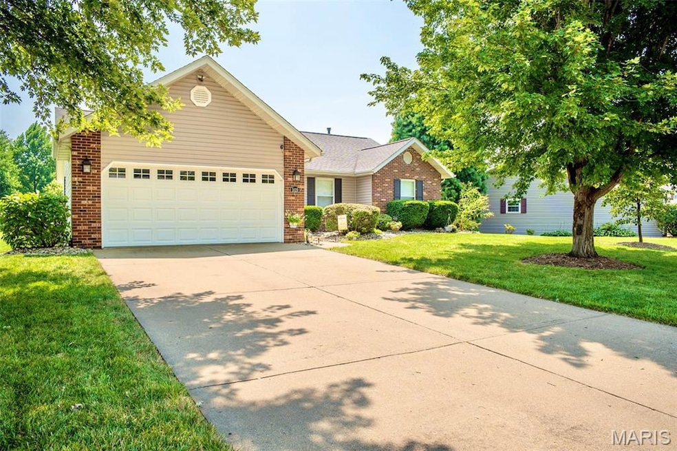View of front of home with driveway, a front lawn, brick siding, and a garage