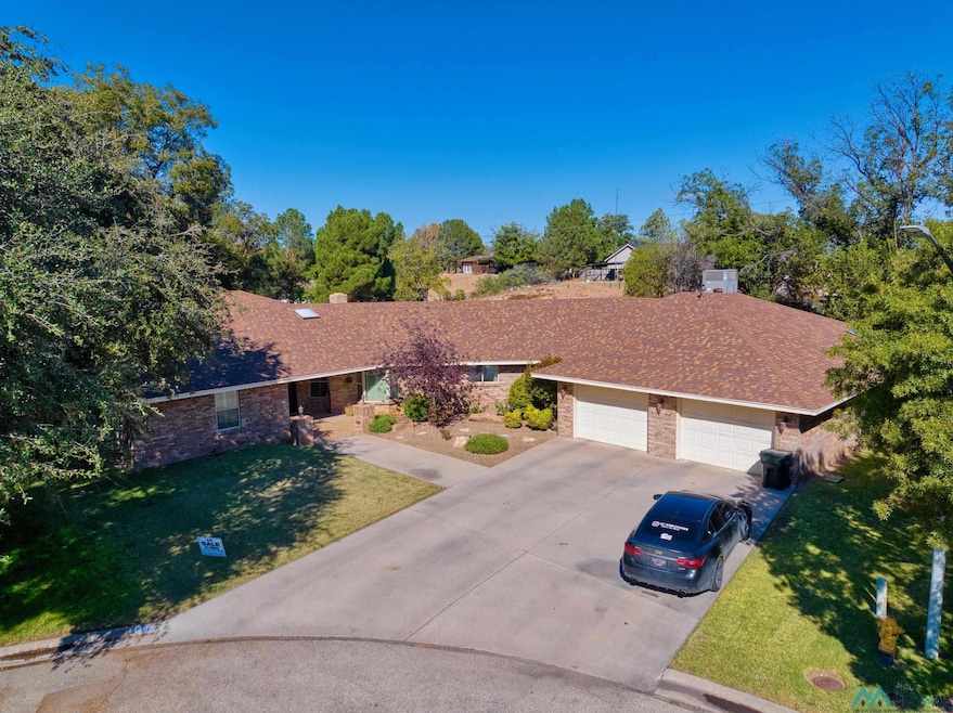 View of front of house with a front yard, concrete driveway, brick siding, a shingled roof, and an attached garage