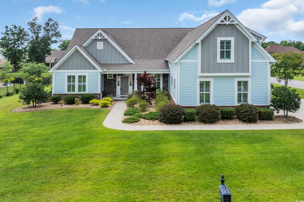 Craftsman-style home featuring board and batten siding, a front lawn, roof with shingles, and stone siding