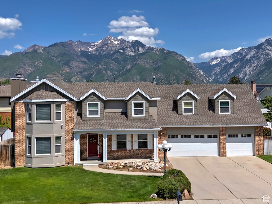View of front of property with brick siding, driveway, a mountain view, and roof with shingles