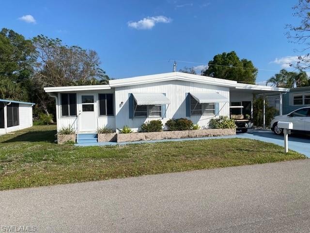 View of front of property with a front yard and a carport