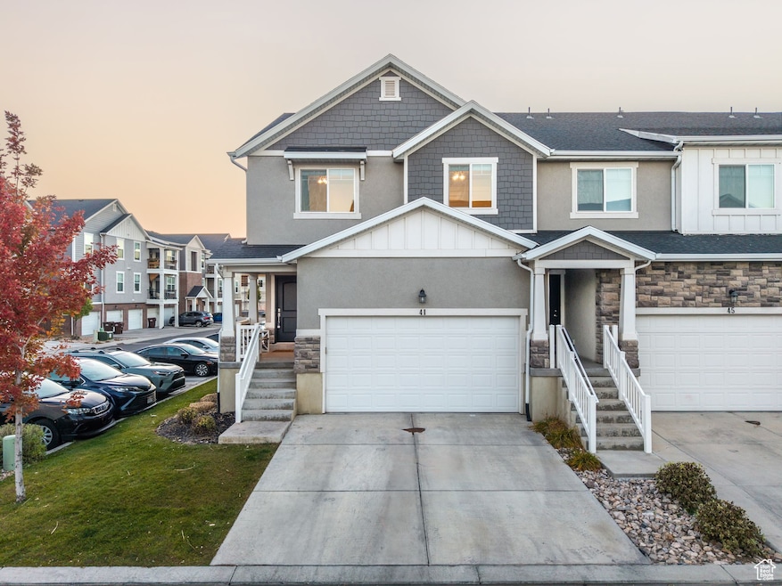View of front facade featuring stone siding, board and batten siding, driveway, and a yard