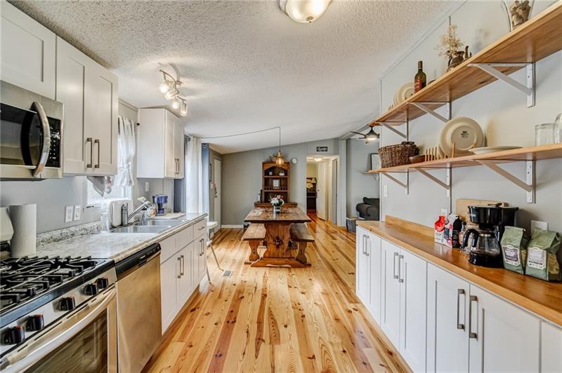 Upgraded kitchen with new cabinetry, open shelving, stainless steel appliances, and heart of pine hardwood floors. All appliances, including the fridge (and washer and dryer) will be staying.