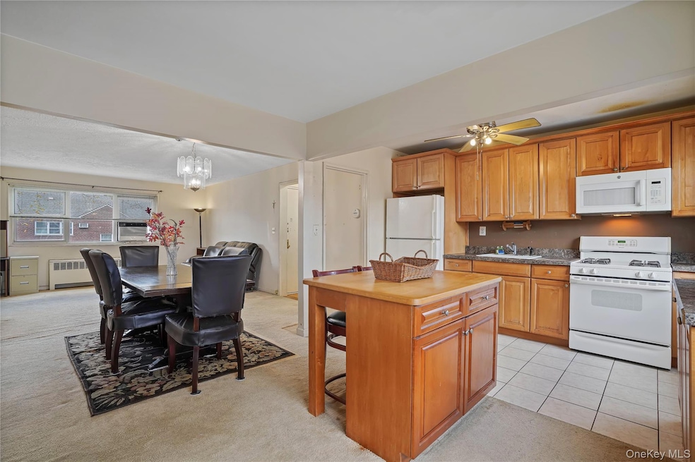 Kitchen with white appliances, brown cabinets, and light colored carpet