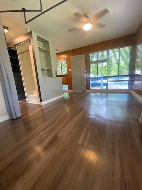 Unfurnished living room with ceiling fan, wood fi
