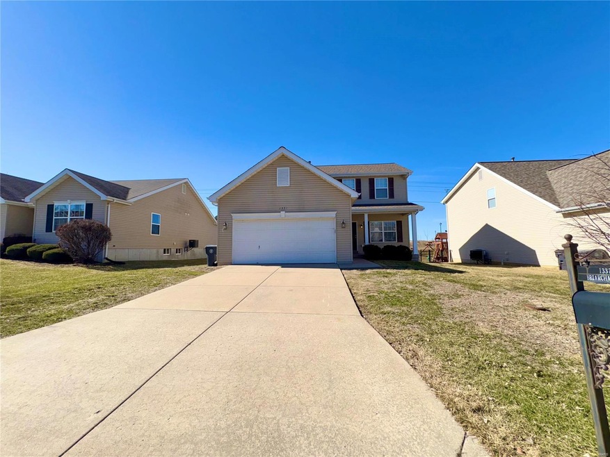 Traditional-style house featuring a garage, driveway, and a front yard