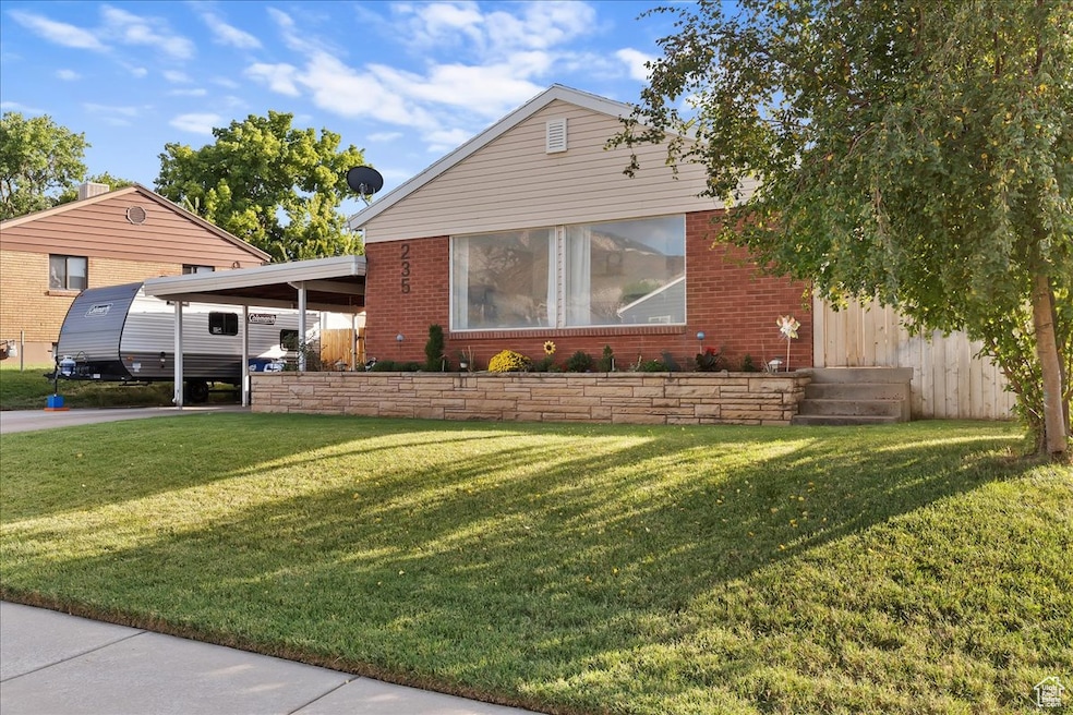 View of front of property featuring a front lawn, a carport, and brick siding