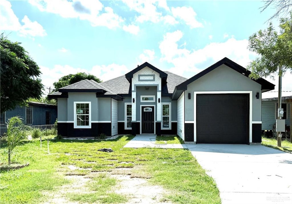 View of front of house with a garage, driveway, a front lawn, a shingled roof, and stucco siding