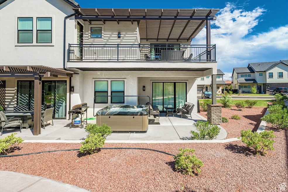 Back of house featuring stucco siding, a patio, a hot tub, and an outdoor hangout area