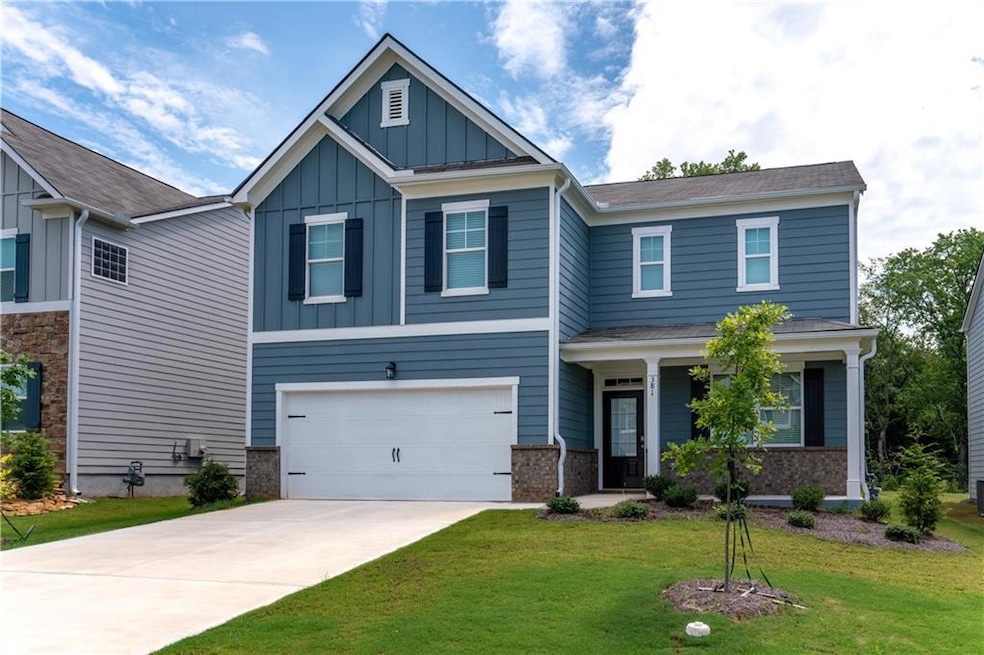 Craftsman-style house featuring board and batten siding, a front yard, driveway, an attached garage, and covered porch