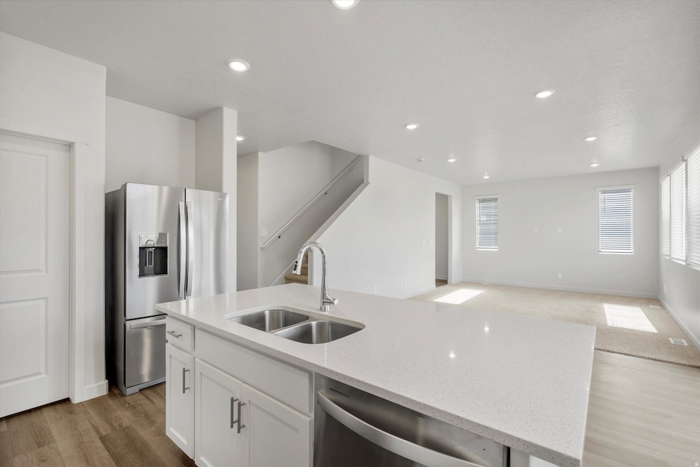 Kitchen featuring stainless steel appliances, an island with sink, open floor plan, light stone counters, and recessed lighting